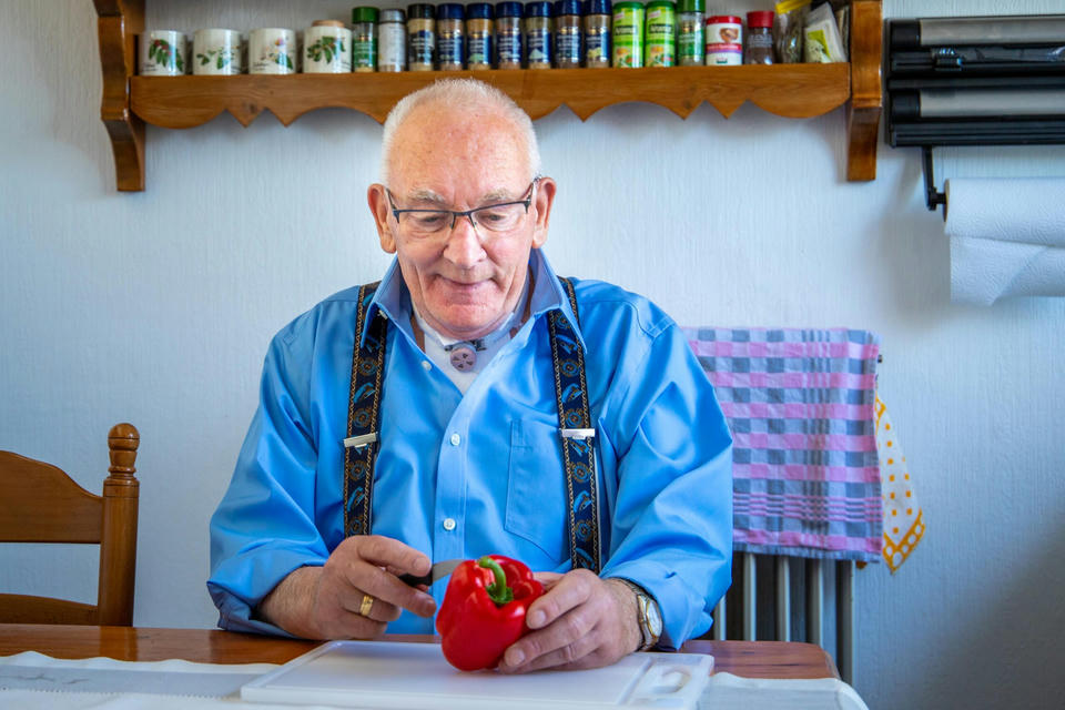 living-with-trachoestomy-man-sitting-at-home man using freevent dualcare cutting vegetable in kitchen